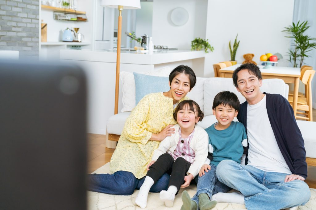 テレビを見ながら笑っている家族